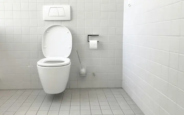 Wall-hung toilet in a white tiled bathroom