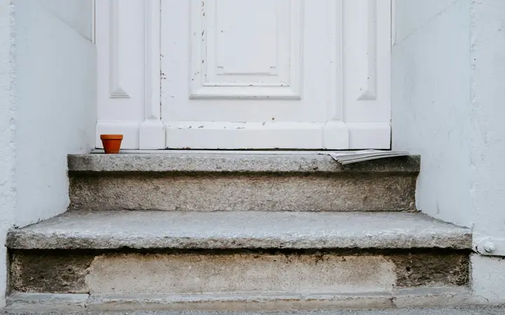 Worn concrete steps leading to a white front door