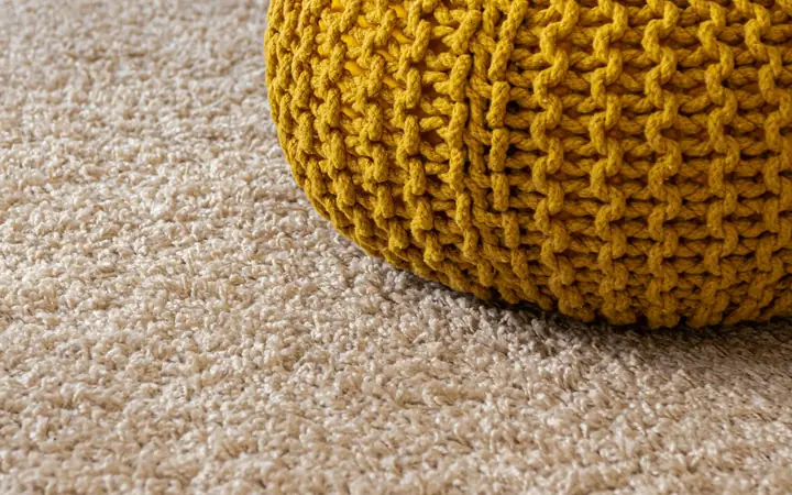 Soft beige carpet with a yellow knitted pouf