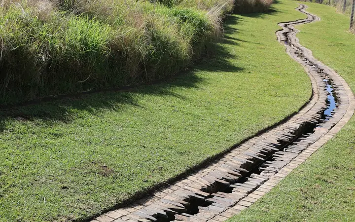 Lined drainage channel running through a sloped lawn