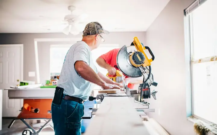 Carpenters cutting trim with a miter saw during a home renovation