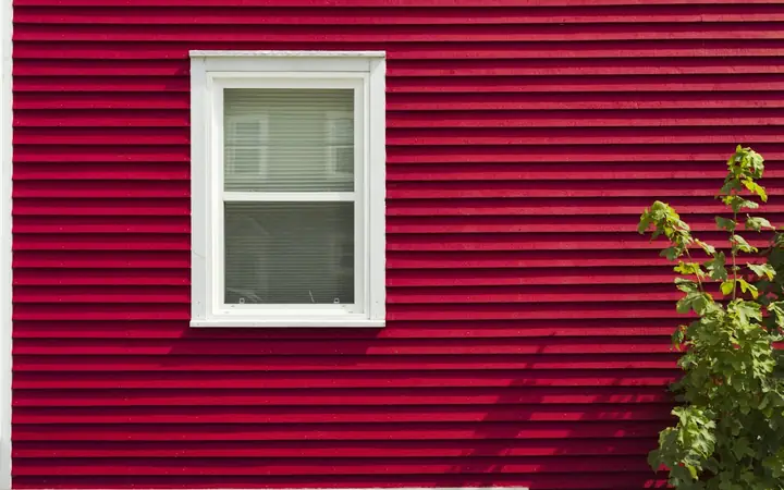 Red horizontal siding around a white window