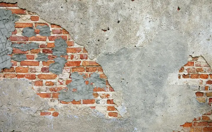 Old wall with exposed brick under worn plaster