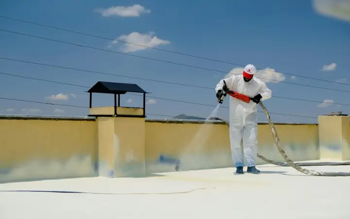 Worker spraying a reflective coating on a flat roof