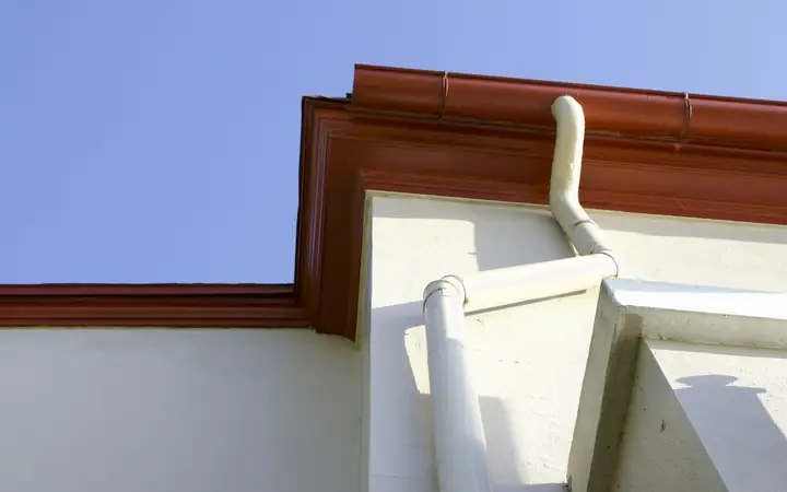 Gutter and white downspout along the edge of a roof