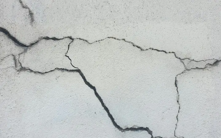 Cracks running across a white stucco wall