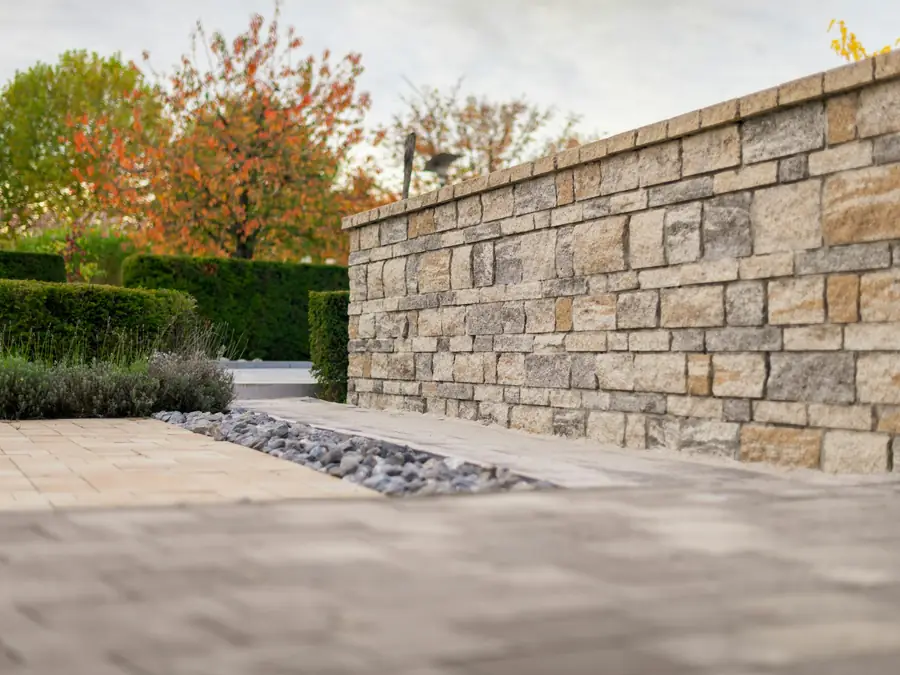 Natural stone garden wall beside a paver terrace